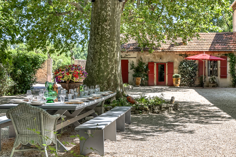 A long table laid for lunch under a plane tree in the courtyard
