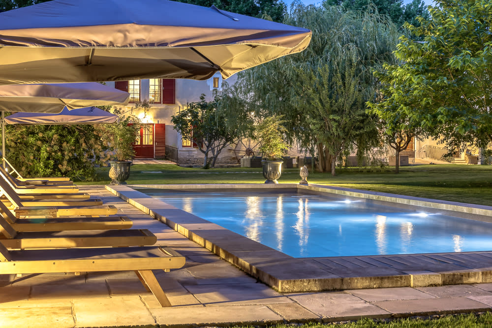 The lit pool and loungers at dusk
